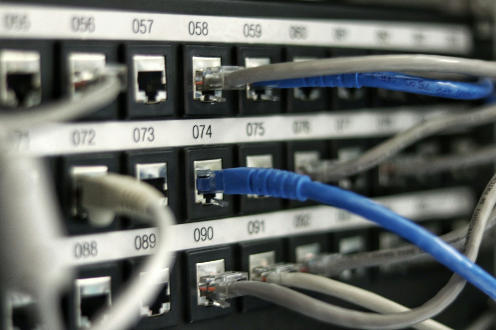 Técnico de infraestrutura e cabeamento estruturado organizando patch panels Cat6A e fibra óptica em rack corporativo